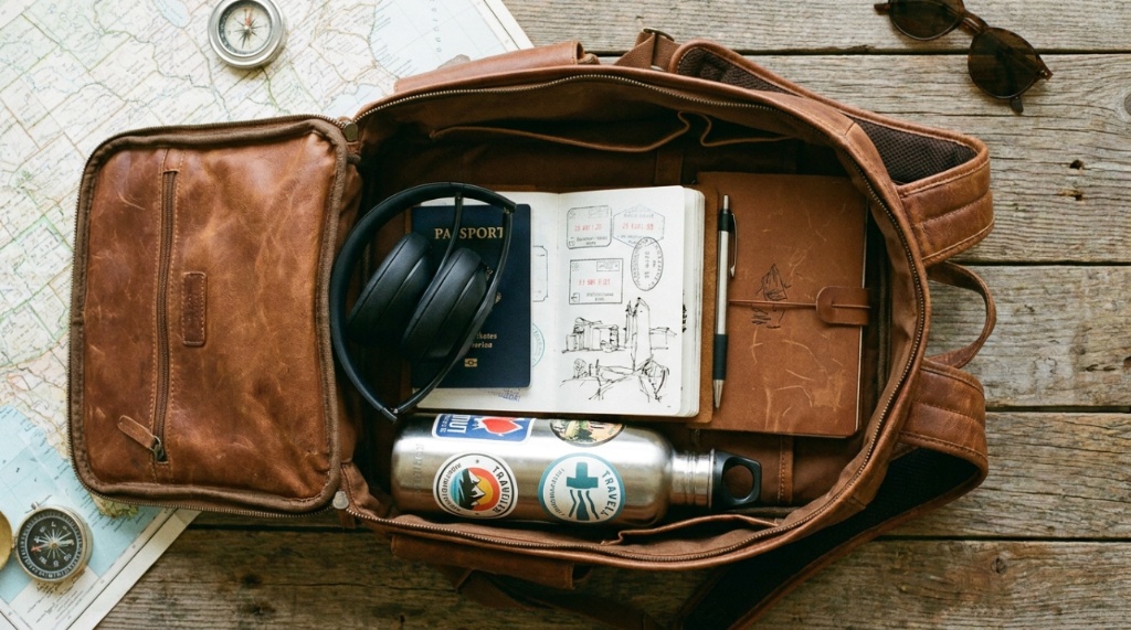 Folded Beats headphones packed inside a travel backpack next to a passport.